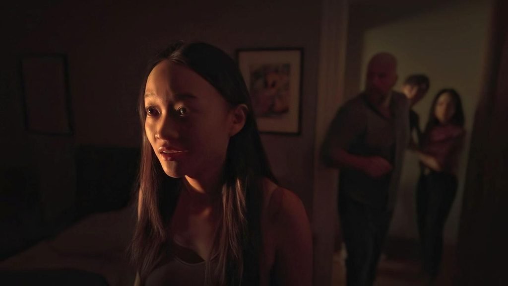 A young woman stands in a dim bedroom while family members gather in the doorway in Presence from Steven Soderbergh