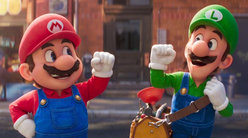 Mario, wearing his red cap and blue overalls, raises his fist toward Luigi, wearing a green cap and blue overalls, on a city street in The Super Mario Bros. Movie.