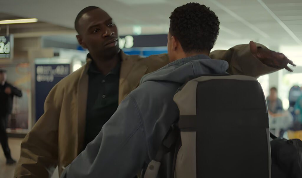 Théo Christine as Raoul embracing his father, Assane Diop (played by Omar Sy), in a terminal setting in Lupin part 4.