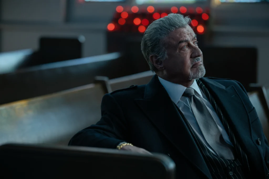 Sylvester Stallone as Dwight Manfredi sitting in a church pew in Tulsa King Season 4