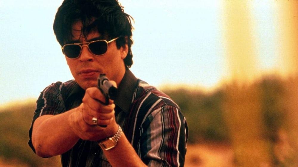 Benicio del Toro wearing sunglasses and aiming a handgun in Traffic (2000)