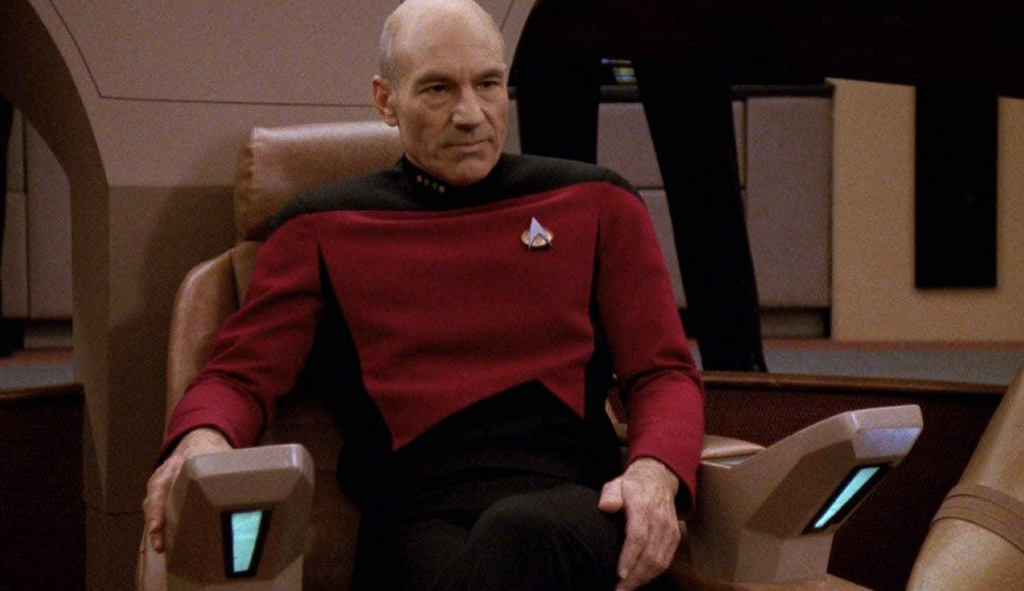 Patrick Stewart as Captain Jean-Luc Picard seated on the USS Enterprise bridge in Star Trek: The Next Generation.