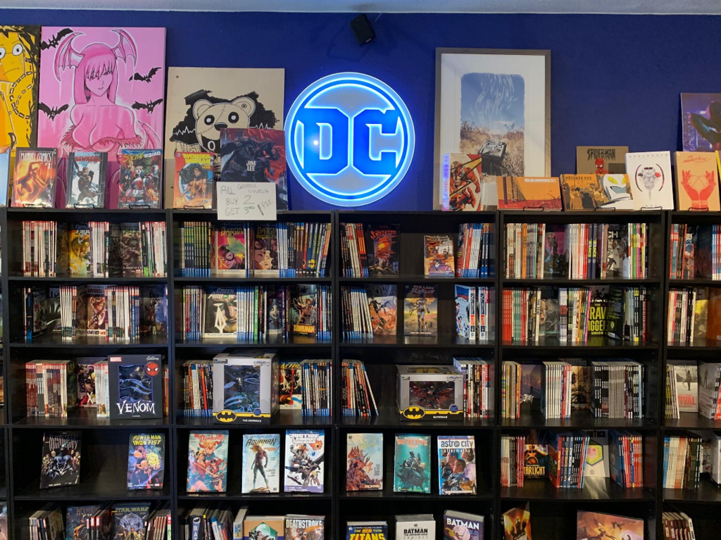 a photograph of an actual comic shop, with readers browsing shelves. After all the executives, corporate logos, and superhero artwork, bring the story back to the people buying the books.