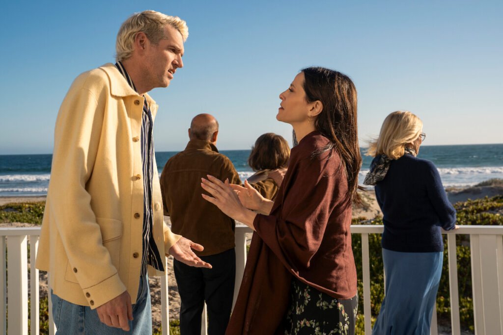 Timothy Simons as Sasha and Jackie Tohn as Esther having an intense conversation on a deck by the ocean in a scene from Nobody Wants This Season 3.