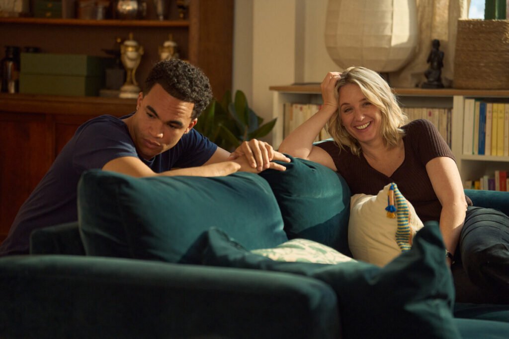 Théo Christine as Raoul and Ludivine Sagnier as Claire sitting together on a blue velvet couch in Lupin Part 4.